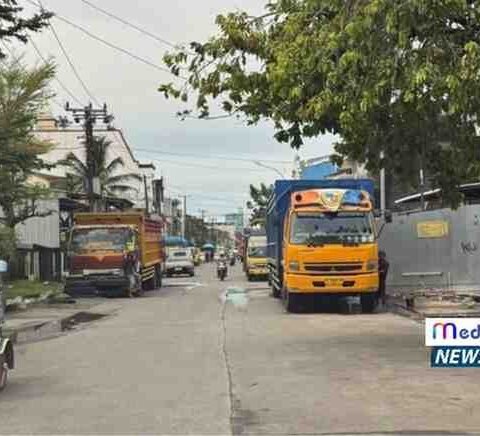 Deretan truk ekspedisi parkir di bahu Jalan Irian Makassar saat bongkar muat, lalu lintas melambat.