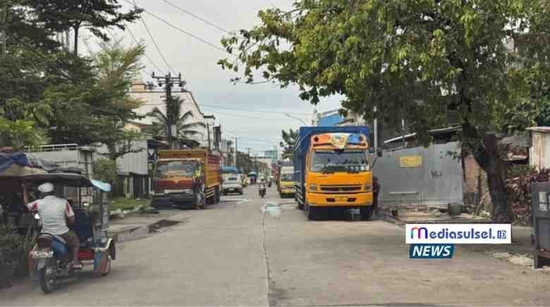Deretan truk ekspedisi parkir di bahu Jalan Irian Makassar saat bongkar muat, lalu lintas melambat.