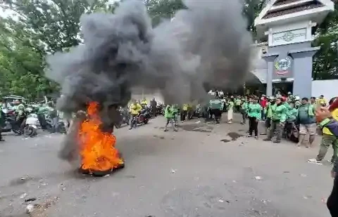 Ratusan driver ojol memblokade Jalan Urip Sumoharjo saat menggelar aksi menolak potongan 10 persen dan status karyawan tetap di depan Kantor Gubernur Sulsel, Senin (24/11/2025).