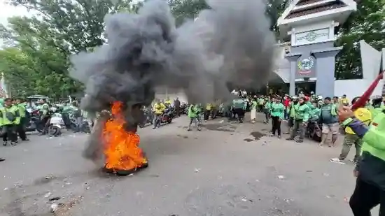 Ratusan driver ojol memblokade Jalan Urip Sumoharjo saat menggelar aksi menolak potongan 10 persen dan status karyawan tetap di depan Kantor Gubernur Sulsel, Senin (24/11/2025).