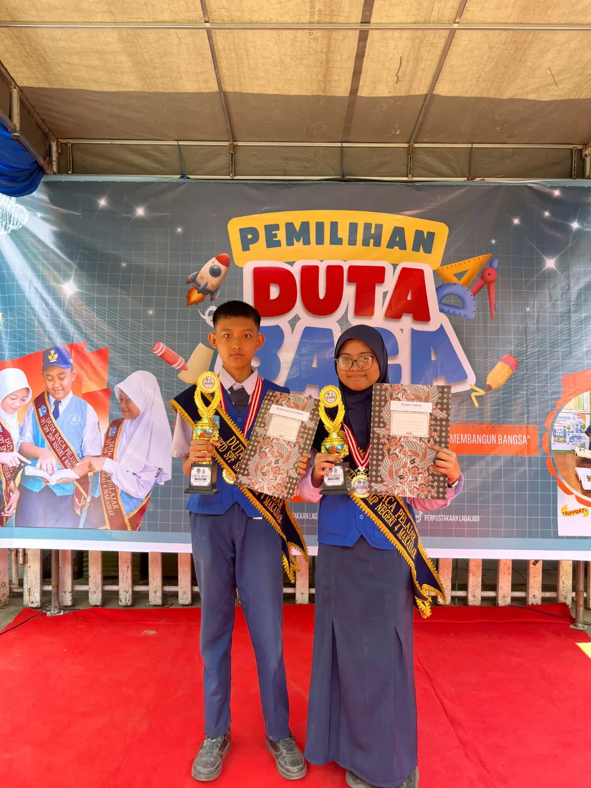 Duta Baca SMPN 4 Makassar Muhammad Faizil Adhim dan Duratun Nafisah membawa piala dan piagam pada 22 Oktober 2026